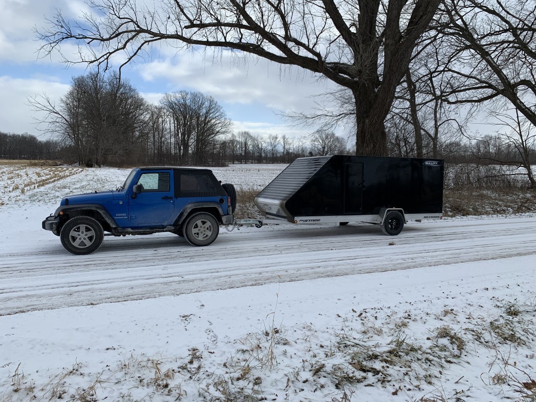 A snowmobile trailer parked on a snowy terrain